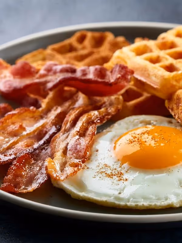 Close-up breakfast plate with waffles, bacon, and sunny-side-up eggs, showing the adult version of the Sir AMPM recipe.