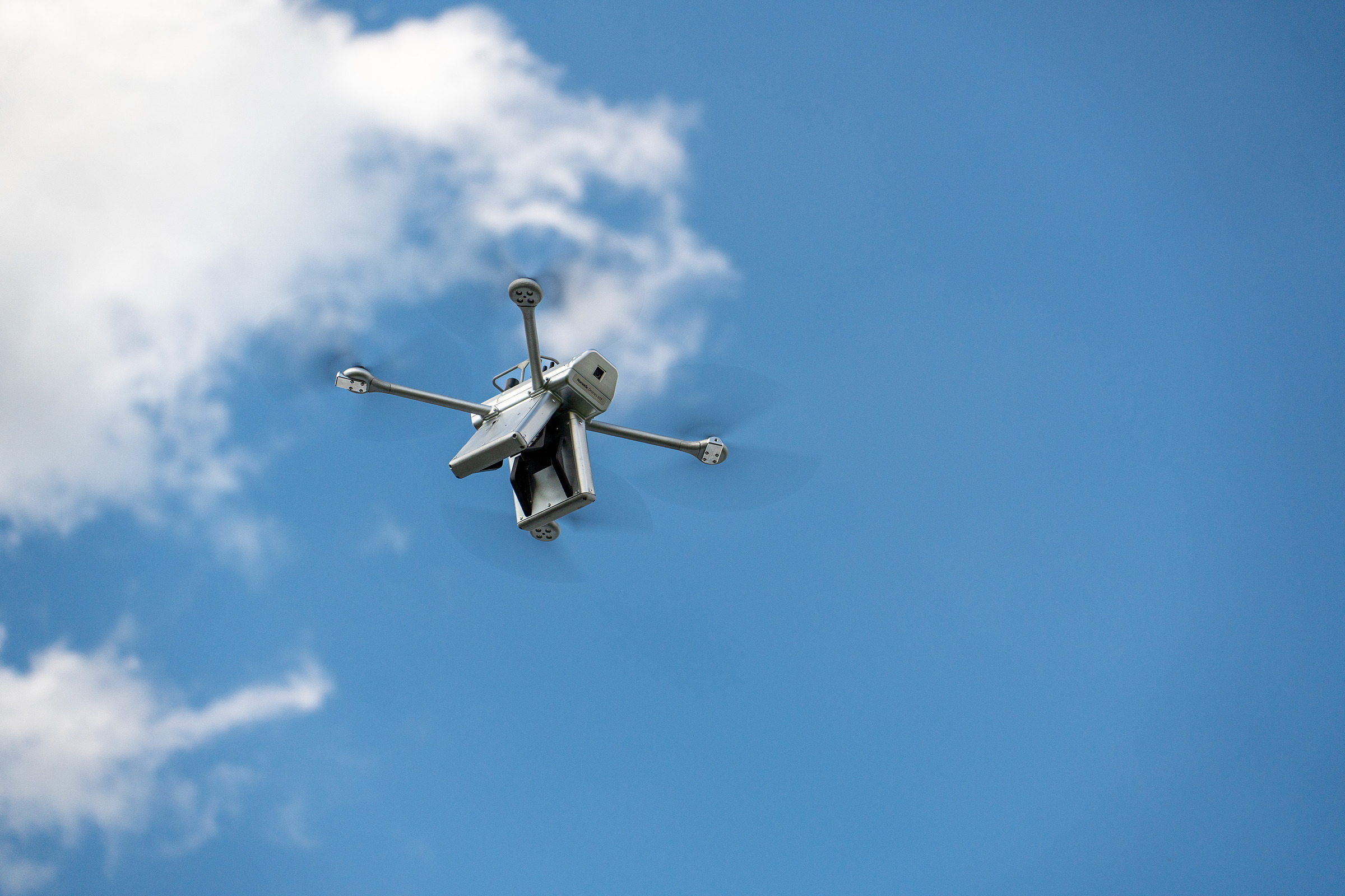 Nomadic drone perched on a high-voltage conductor at sunset