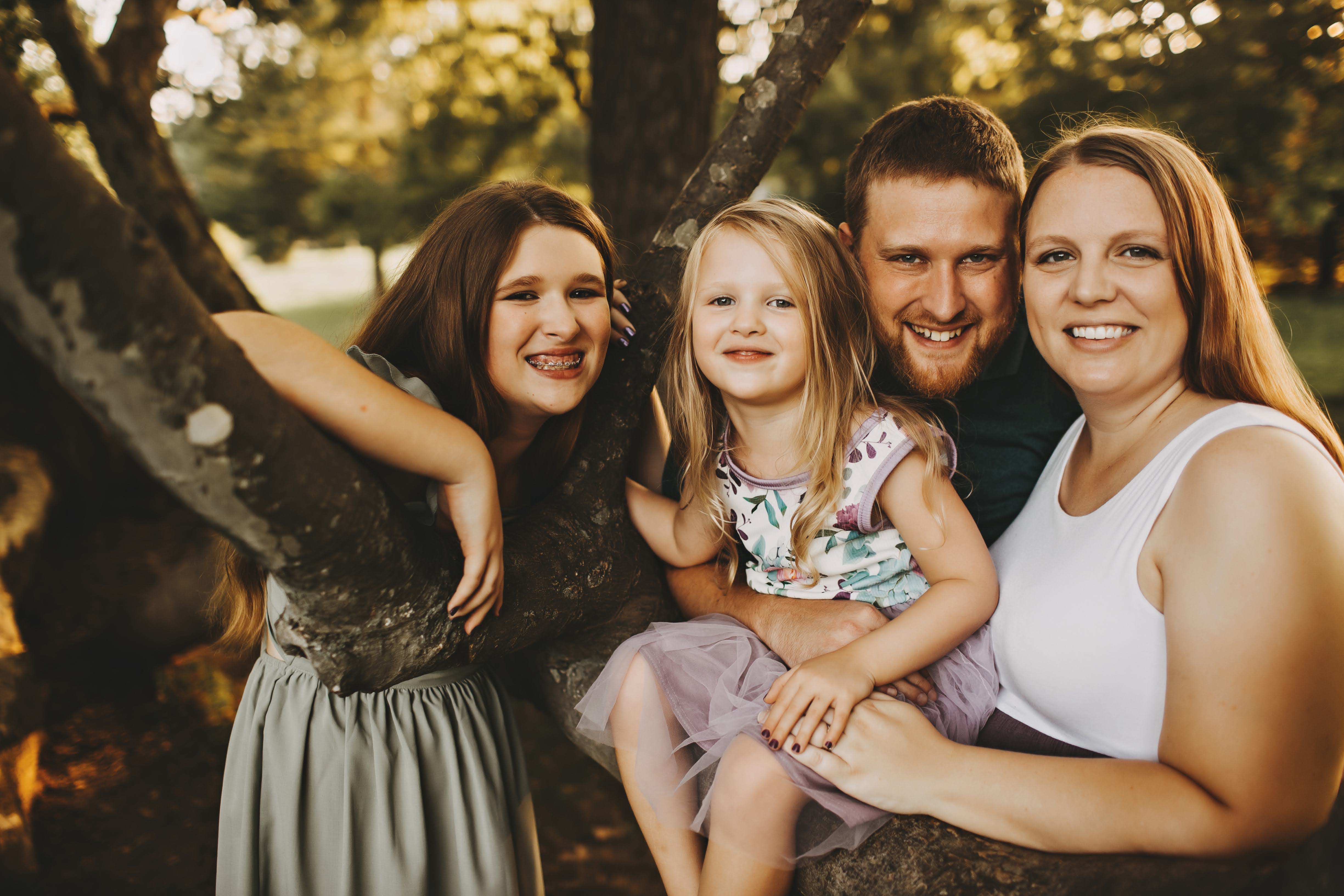 Lance Fogle with his wife and two daughters in a golden-hour outdoor family portrait