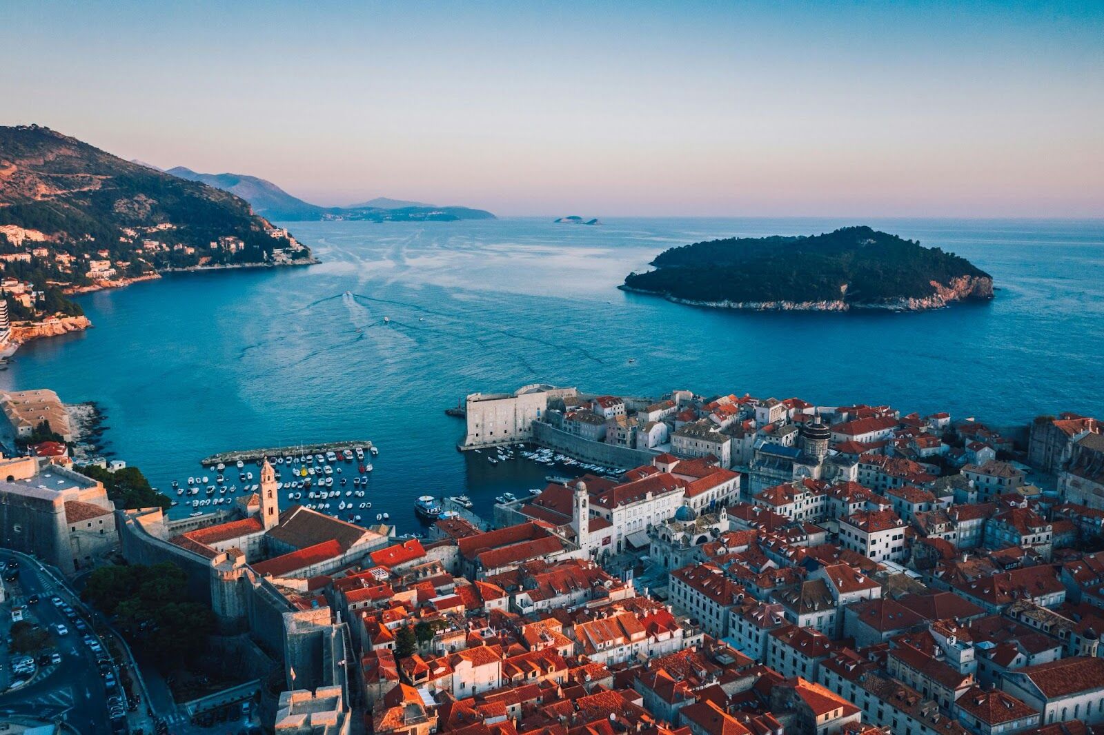 Aerial view of Dubrovnik Old Town with orange rooftops, medieval walls, and the Adriatic Sea.