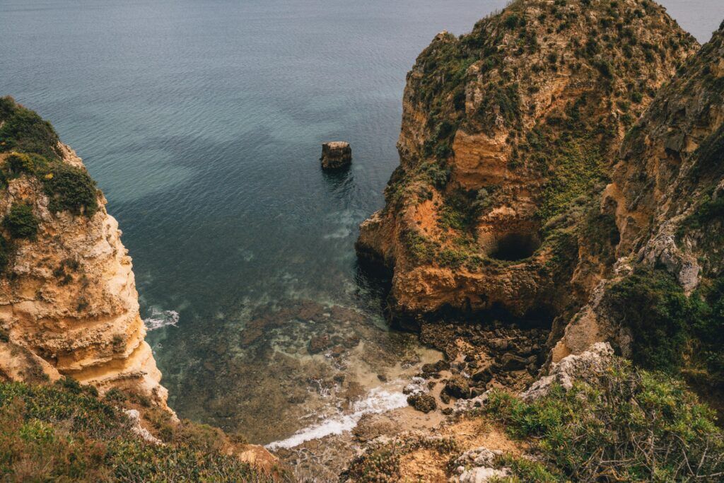 Rocky coastal cliffs with clear blue water and sea caves below.