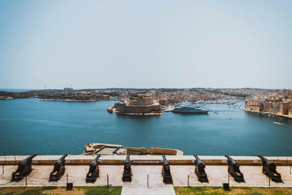 View of Valletta’s Grand Harbour in Malta with historic cannons, stone forts, and yachts.