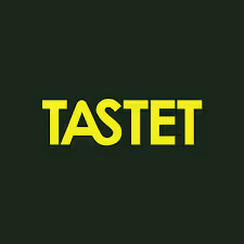 Yellow capital letters spelling TASTET on a dark green background.