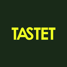 Yellow capital letters spelling TASTET on a dark green background.