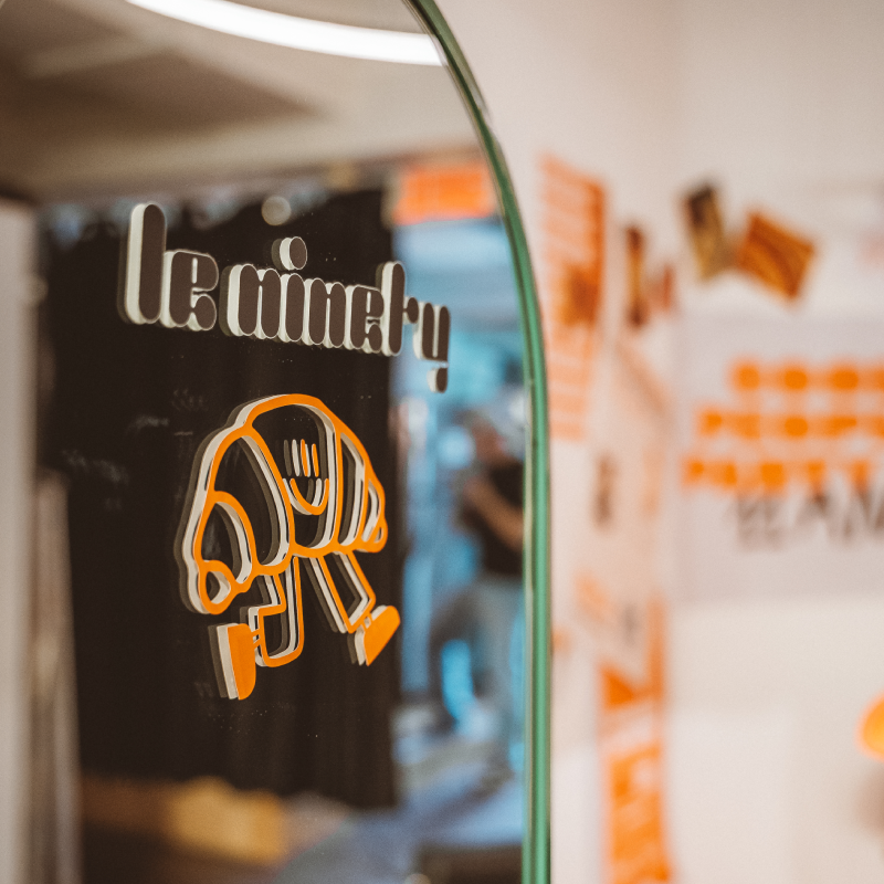 Glass door with an orange and white logo of a walking jacket and the text 'le ninety' in retro font.