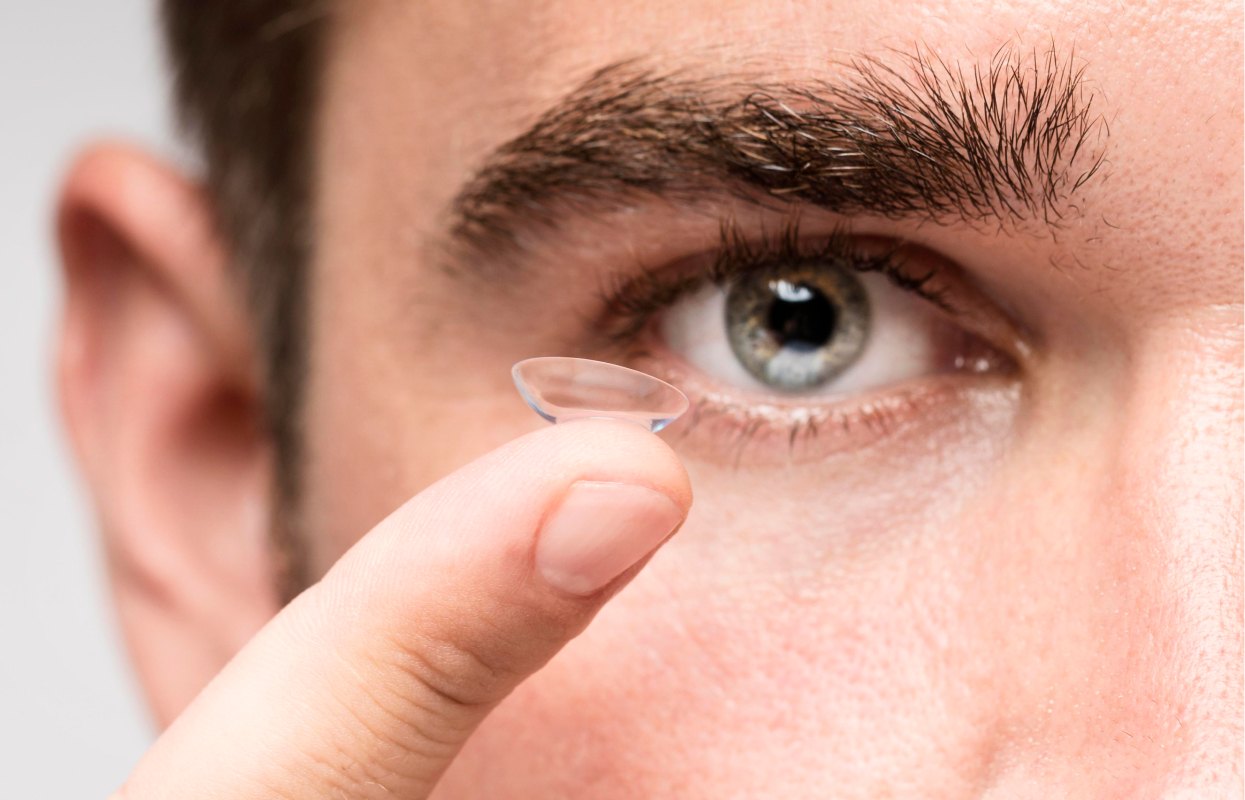 A man holding a contact lens up to his eye