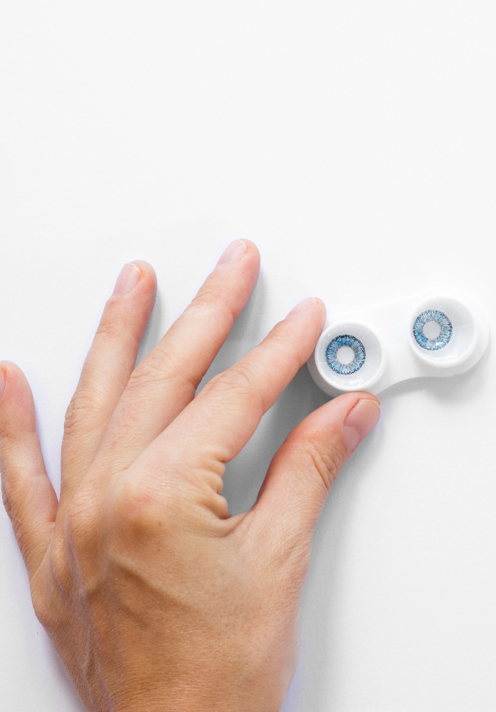 A hand holding a pair of contact lenses