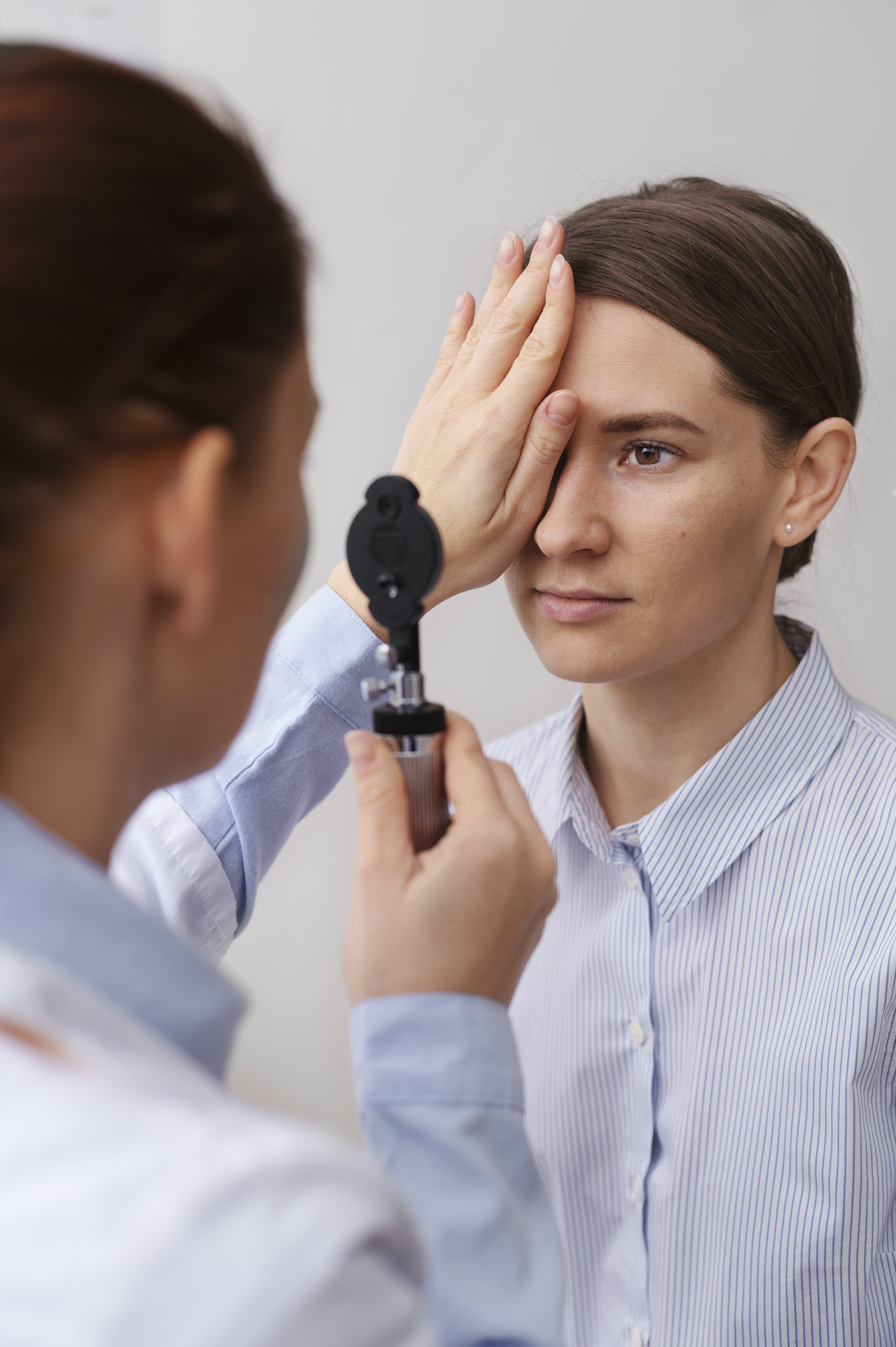 Doctor examining patient's eye with optical instrument during medical vision test