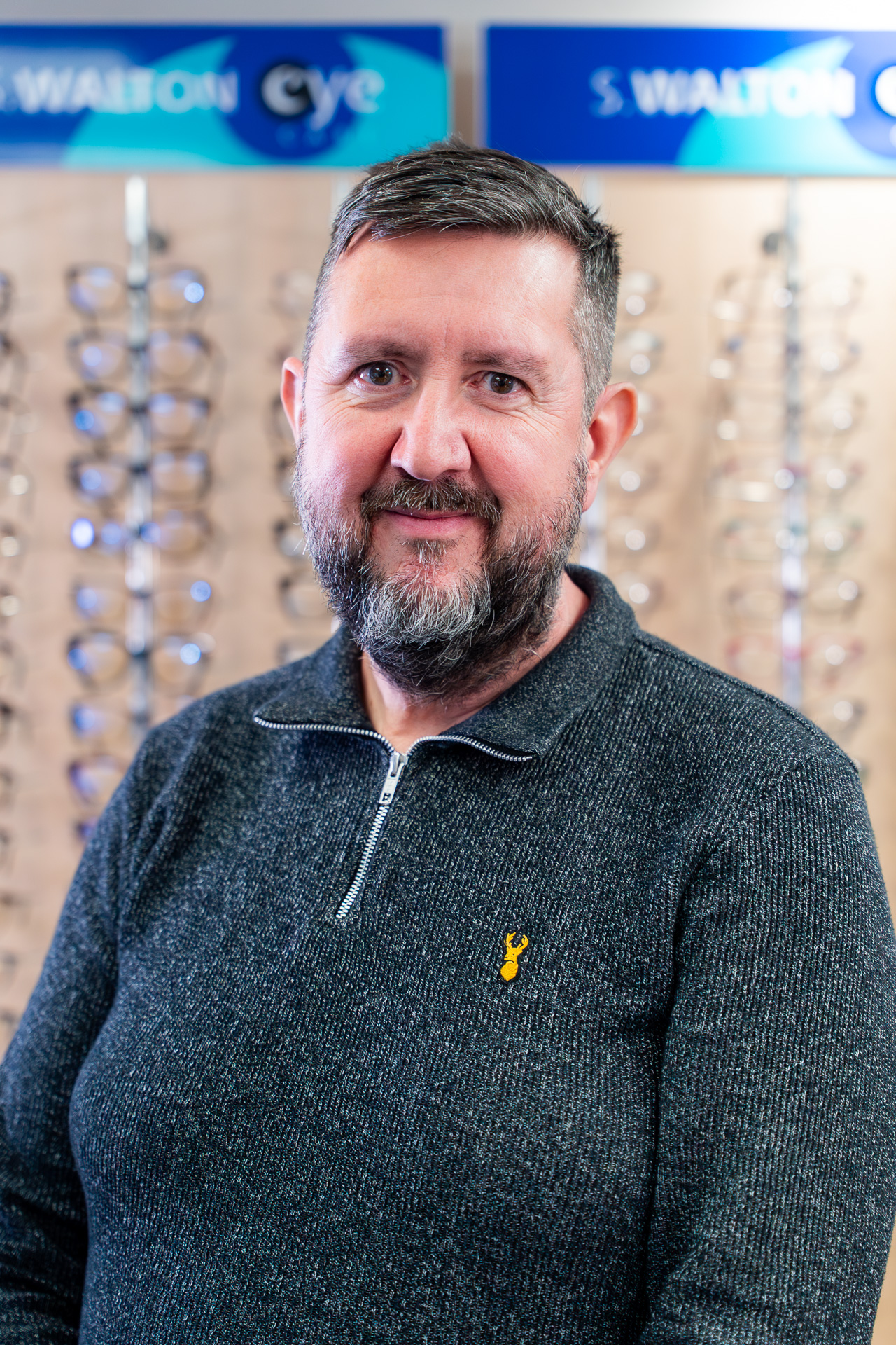 Man with beard in optometrist office with eyewear displays and signage