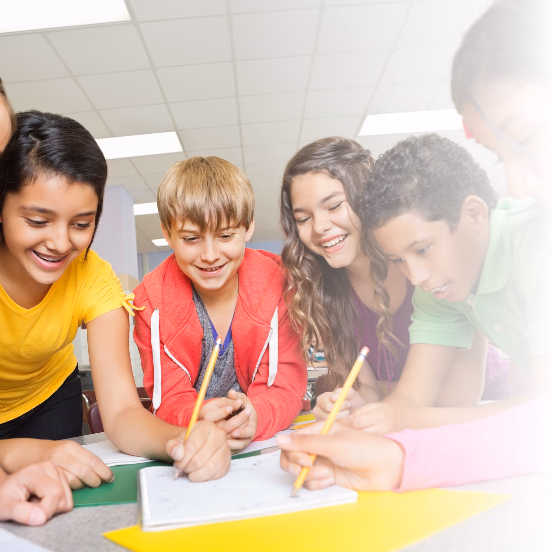 Middle School Students drawing with pencils as a group around a table.