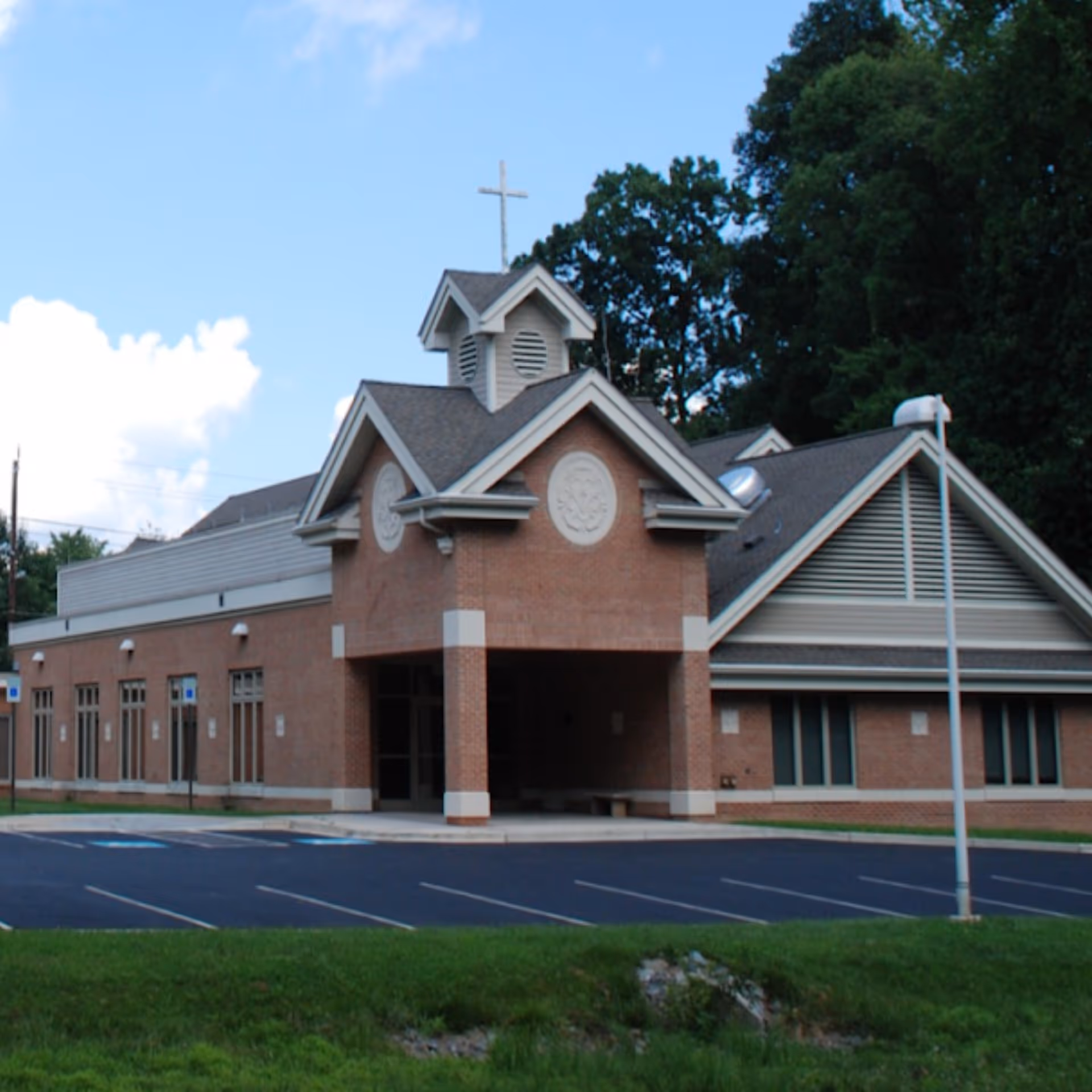 A picture of a brick building with a cross on the roof.