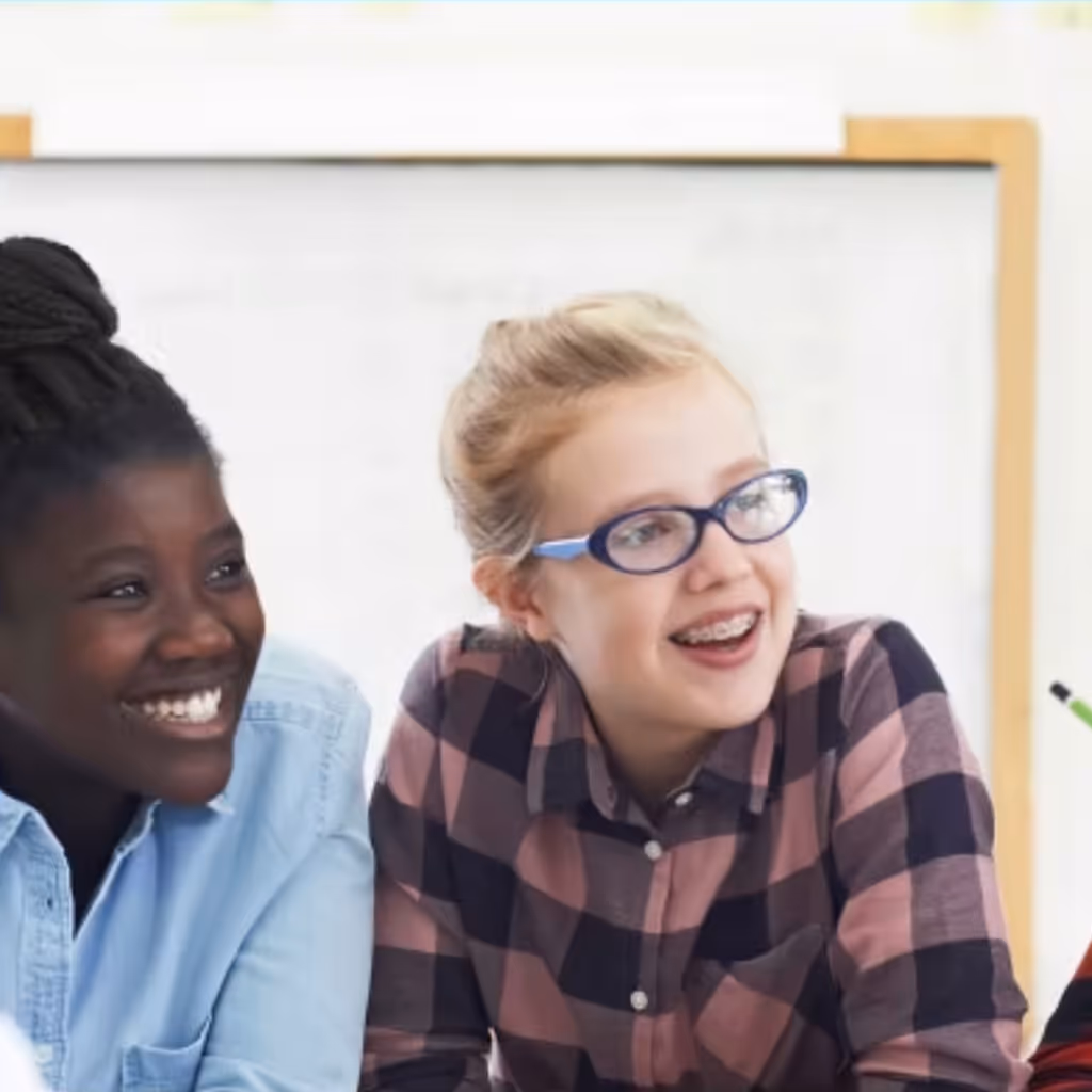 Two female students smiling in a classroom.