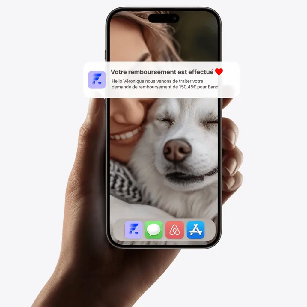 Un téléphone tenu dans une main affiche une notification de remboursement de 150,45€ pour un chien nommé Bandi, avec en arrière-plan le visage souriant d'une femme et un chien aux yeux fermés.