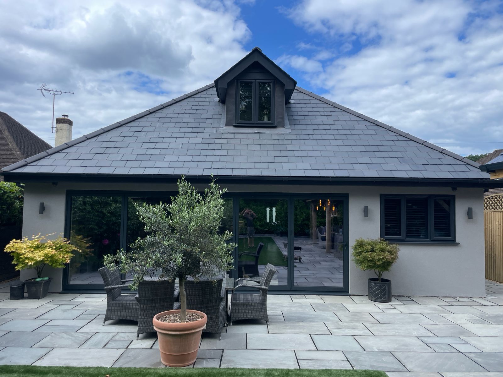 Renovated home with loft extension featuring grey roof, dormer window, and modern exterior finish