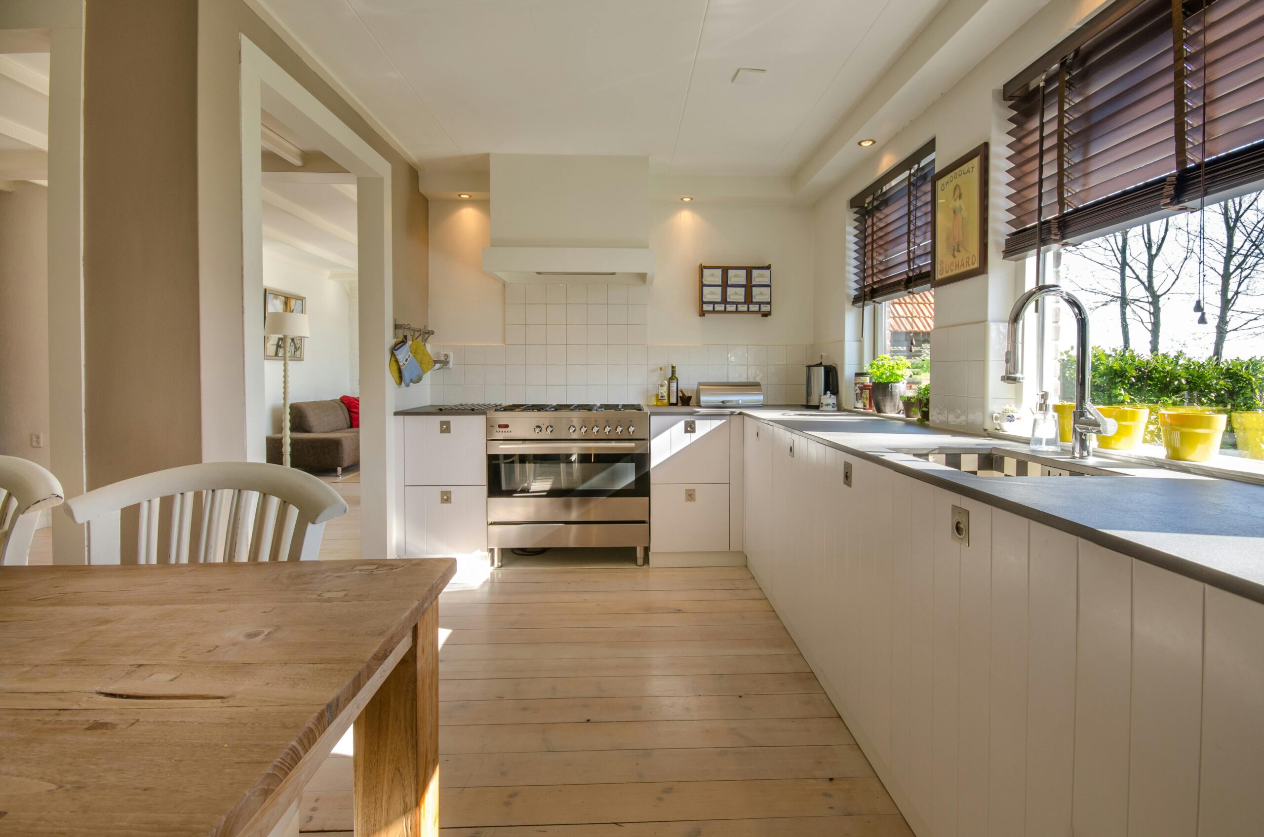 A modern white kitchen with wooden dining table and large oven.
