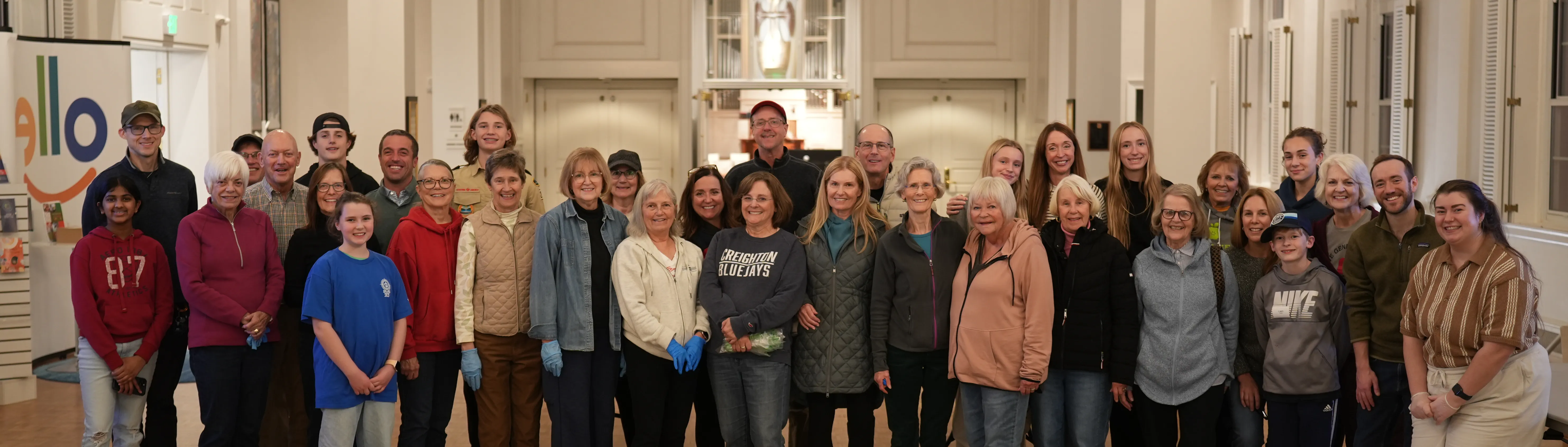 Large group of diverse people of various ages smiling together indoors in a well-lit room.