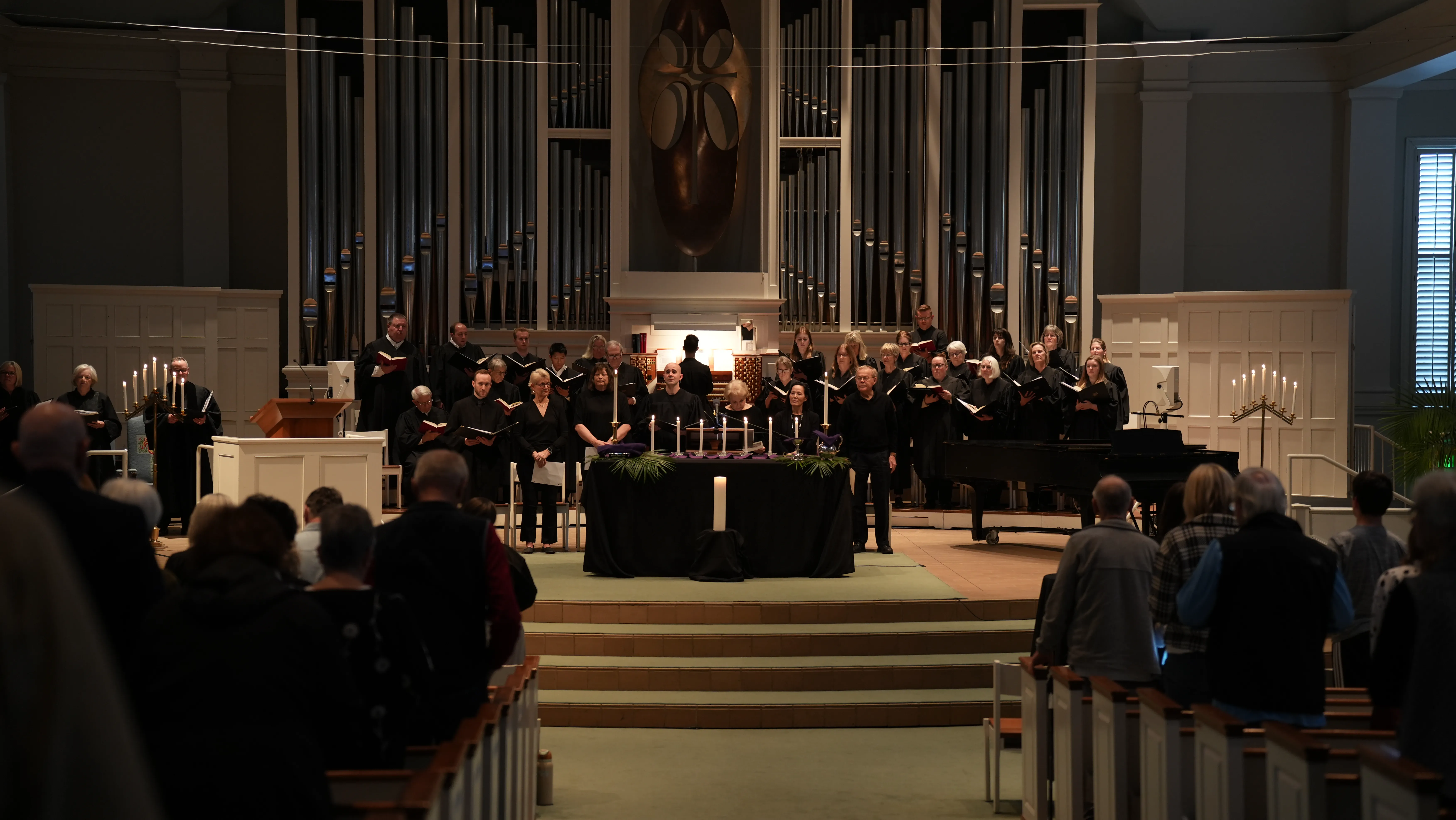 Congregation and choir in a church during a Maundy Thursday service with candles and an organ in the background.