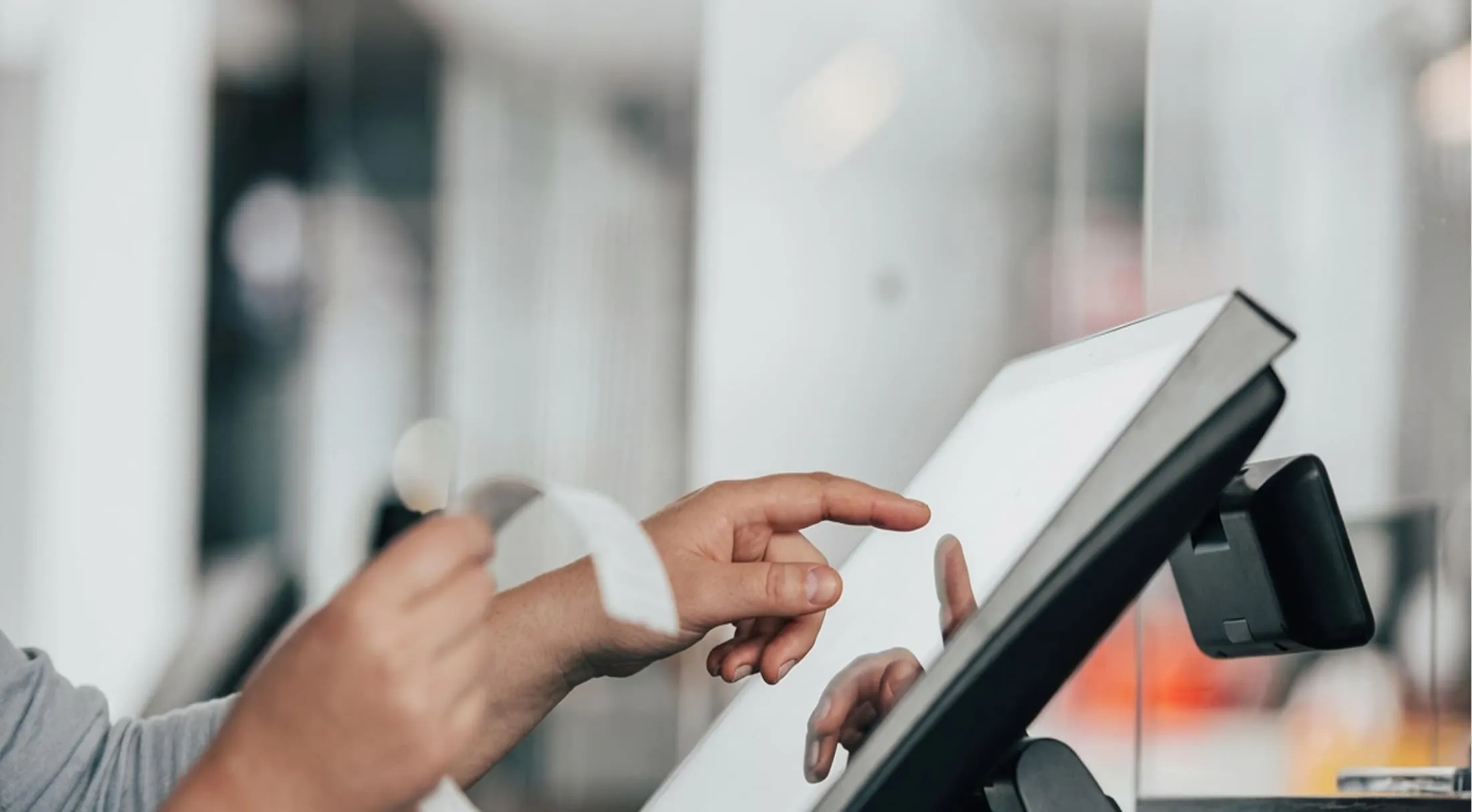 Person utilisant un écran tactile de caisse enregistreuse tout en tenant un reçu.
