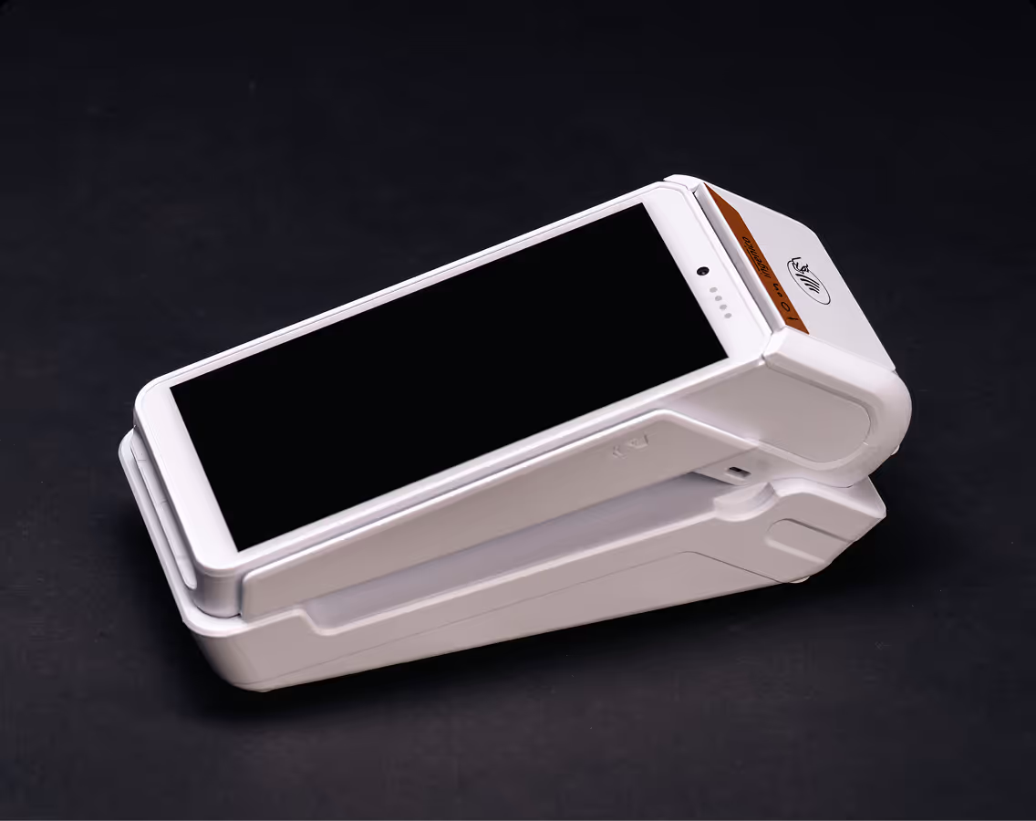 Terminal de paiement blanc avec écran tactile noir incliné sur fond noir.