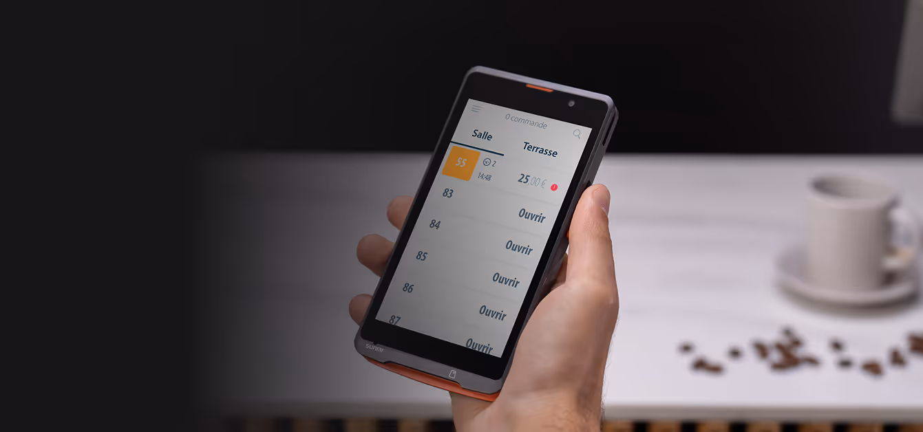 Une main tient un appareil de point de vente affichant une liste de commandes avec des options pour ouvrir chaque table.