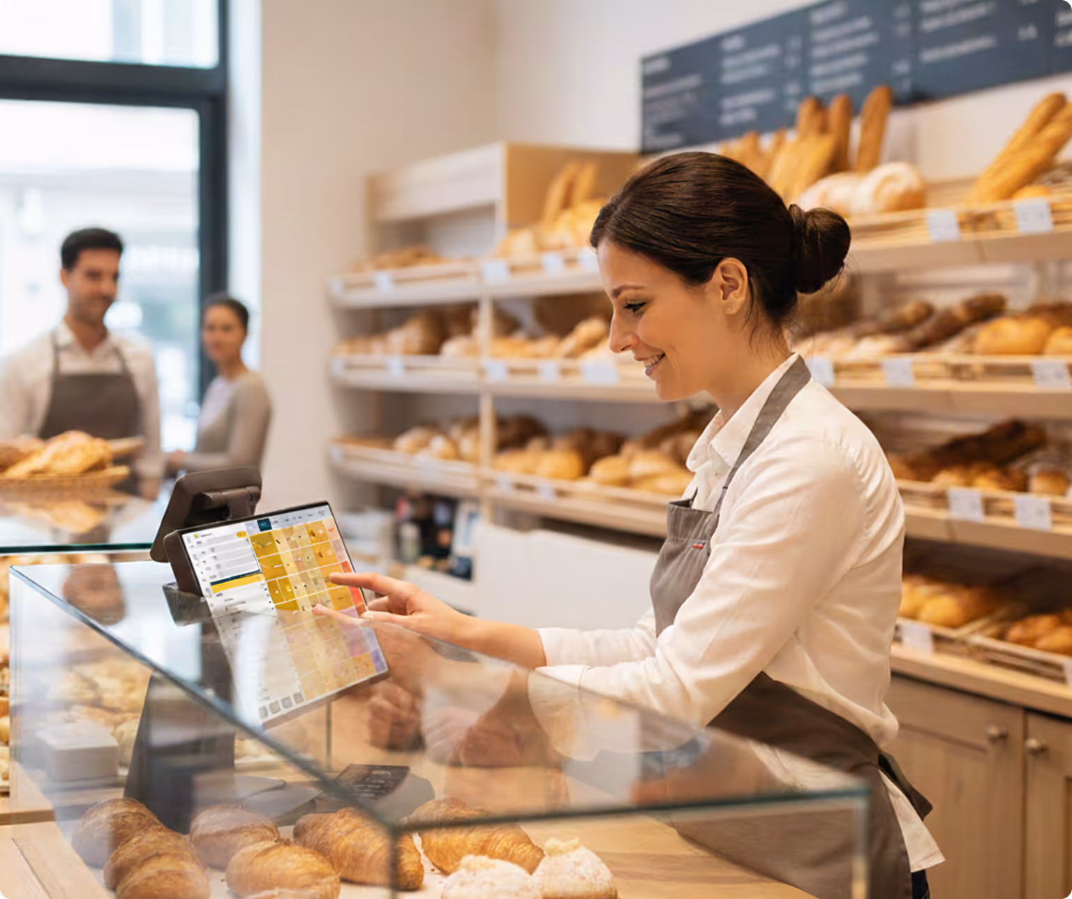 Employée de boulangerie en train de taper la commande d'un client sur son écran de caisse conçu pour le métier de boulanger