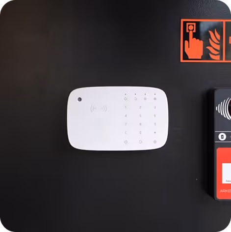 Clavier d'alarme blanc mural avec chiffres tactiles et icônes d'état lumineux sur fond noir.