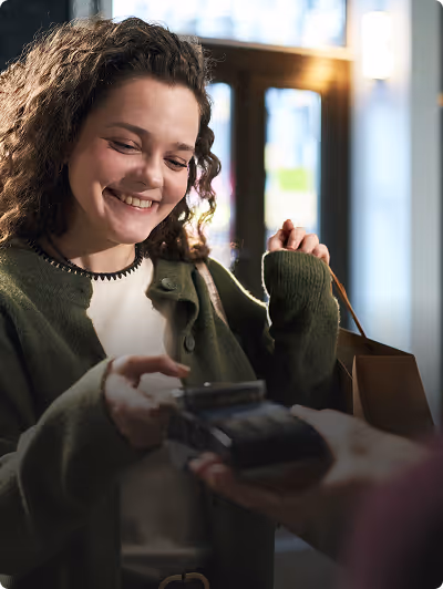 Jeune femme souriante utilisant un terminal de paiement pour régler un achat en magasin et récompensé grâce à son programme de fidélité.