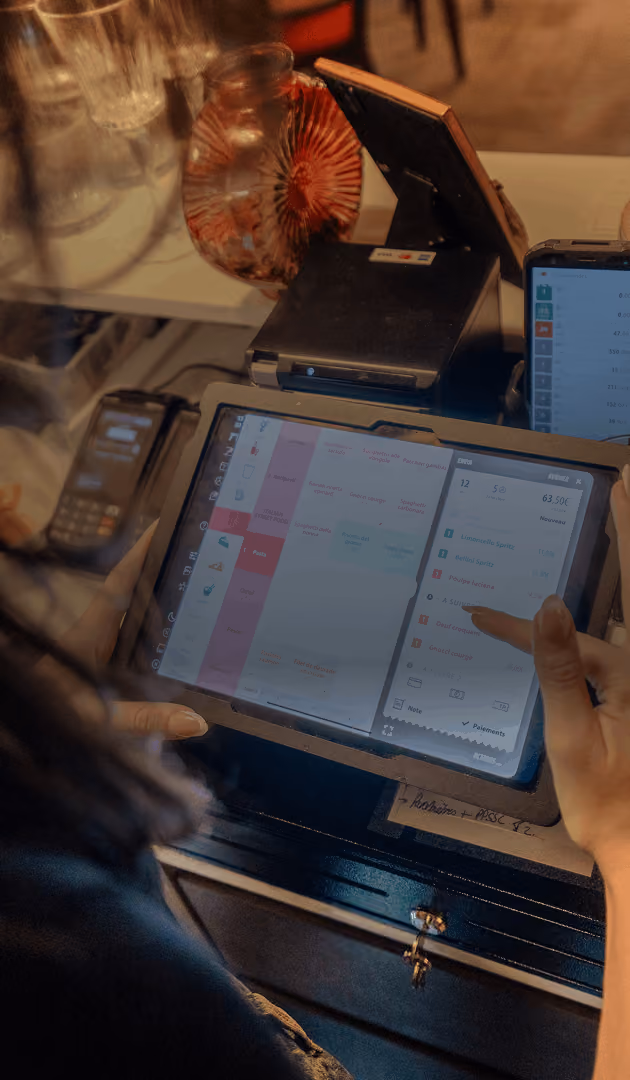 Personne utilisant une tablette tactile pour gérer des commandes sur une caisse enregistreuse à Montpellier moderne.