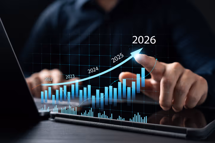 Person pointing at a digital bar graph with an upward trend from 2022 to 2026 displayed over a tablet.