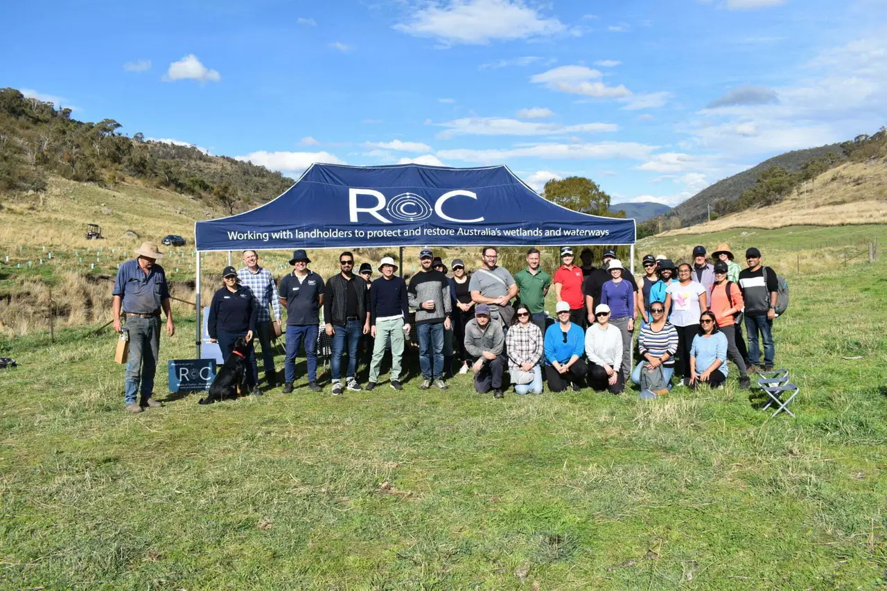 Group of people posing outdoors in front of a blue tent with ROC logo and text about protecting Australia's wetlands and waterways.