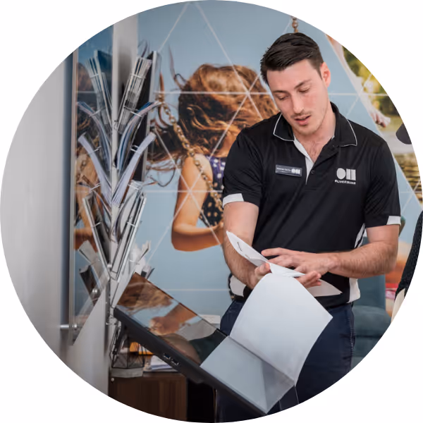 Man in black polo shirt reviewing documents in a modern office setting with colorful wall art.