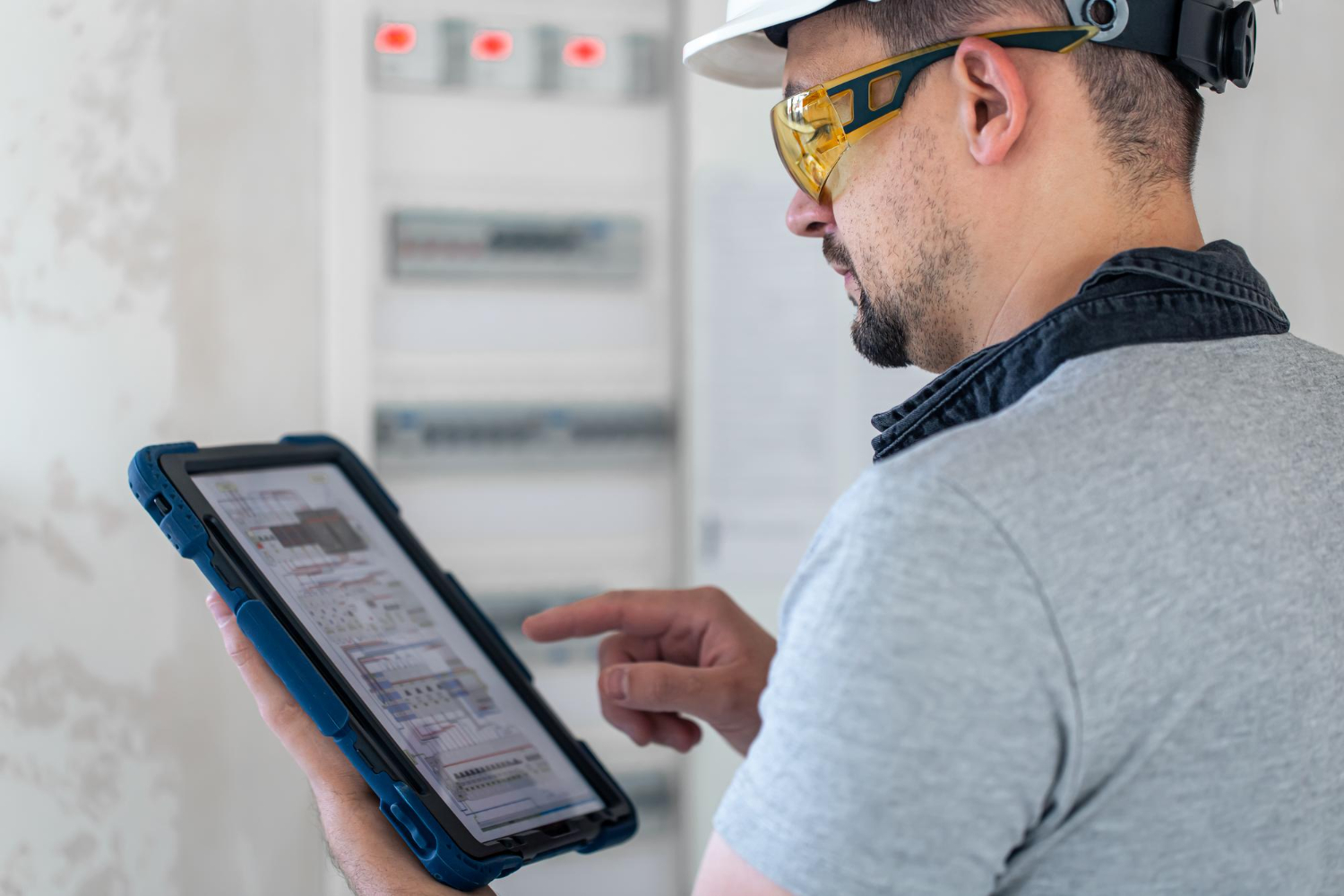 Advanced manufacturing technician consulting technical schematics on a tablet while troubleshooting equipment