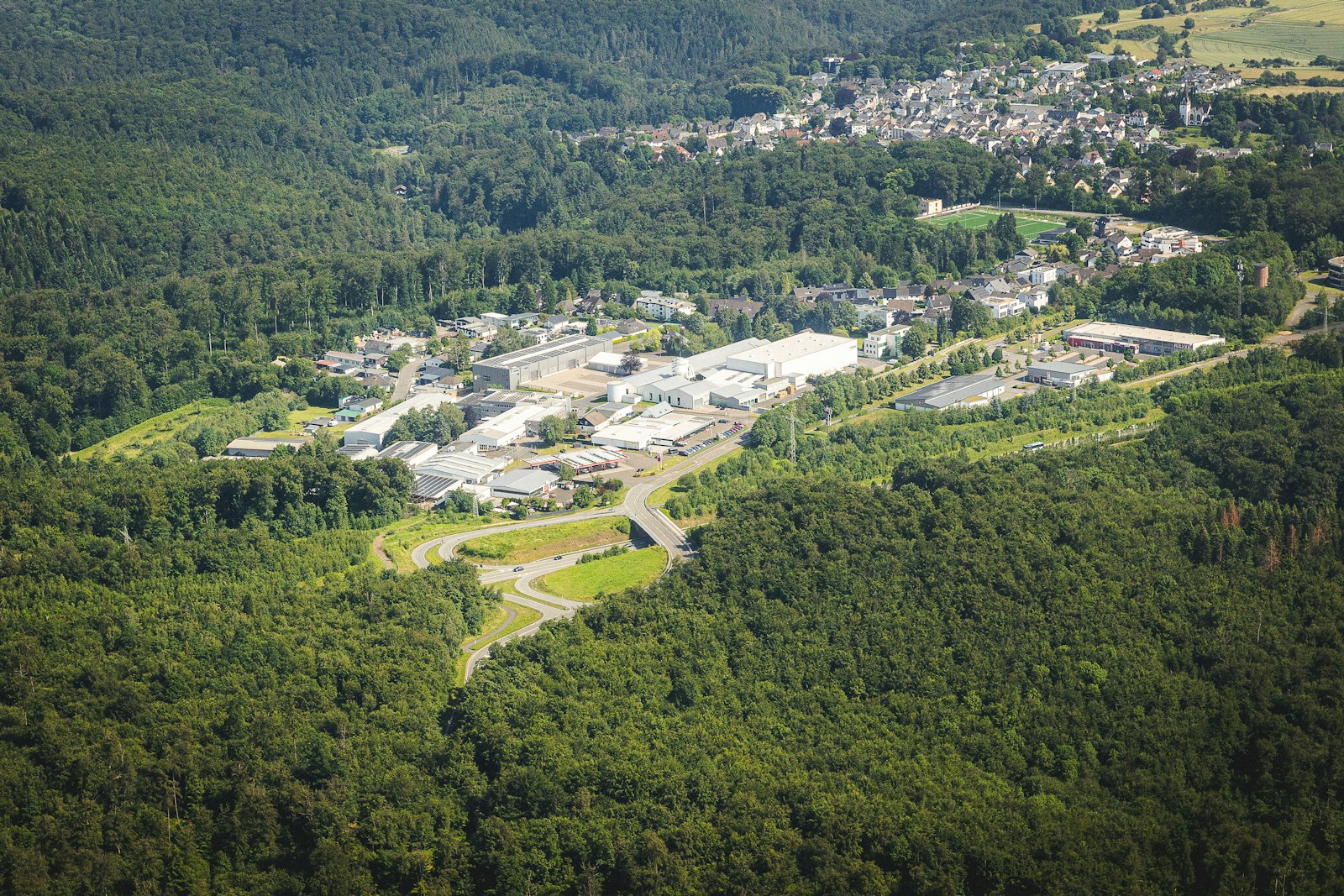 Manufacturing facility beside a small rural town surrounded by forest