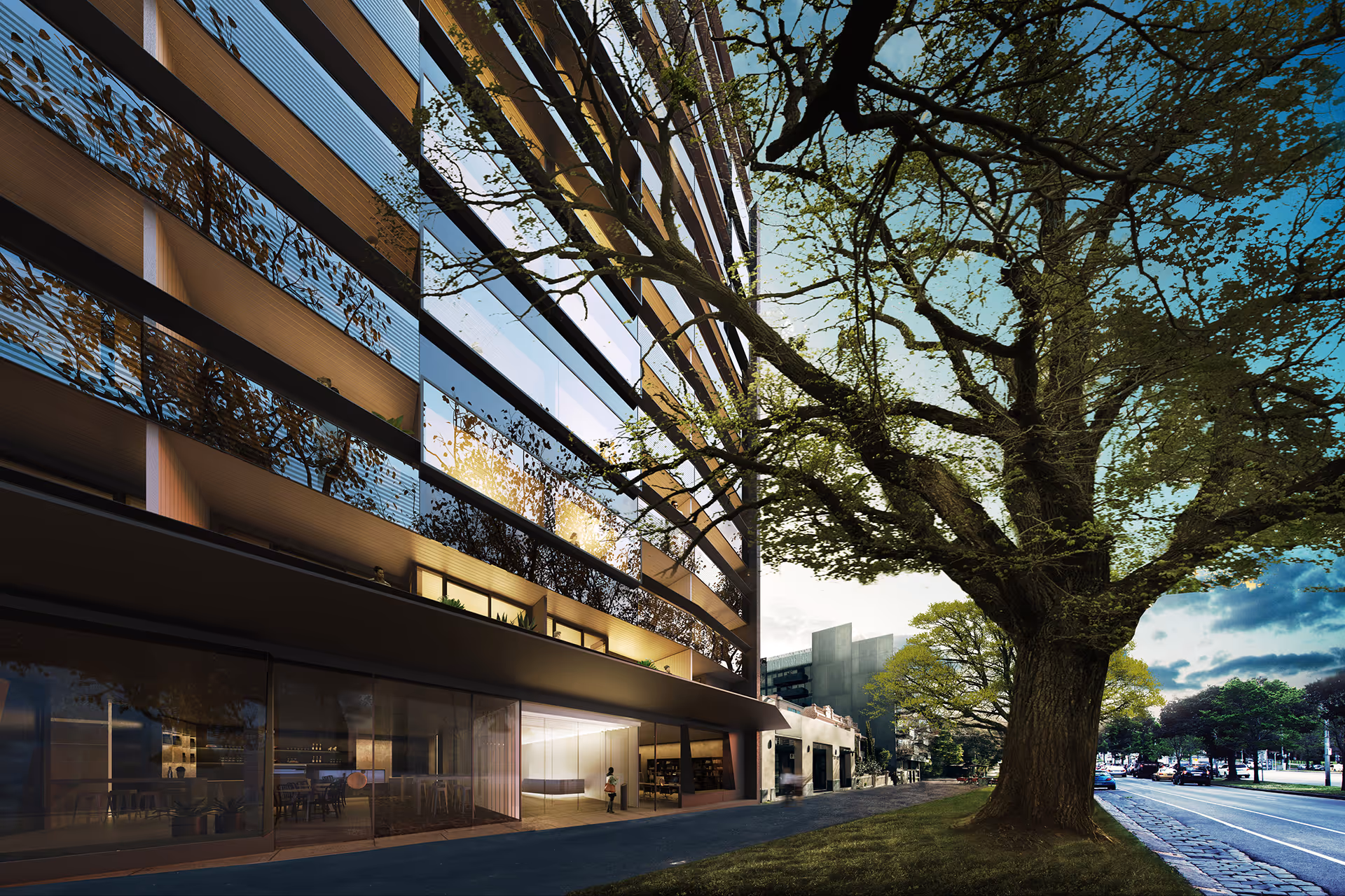 Modern high-rise building with reflective glass façade beside a large mature tree at dusk.
