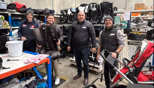 Men in warehouse with stroller and car seat.