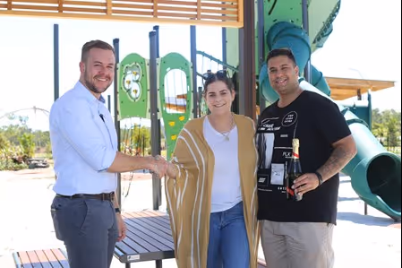 Three people posing in front of play equipment.