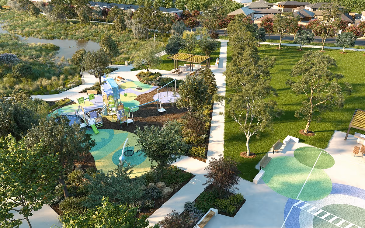 Playground with slides, swings and colourful rubber flooring beside landscaped paths, trees and open grass areas in a modern park.