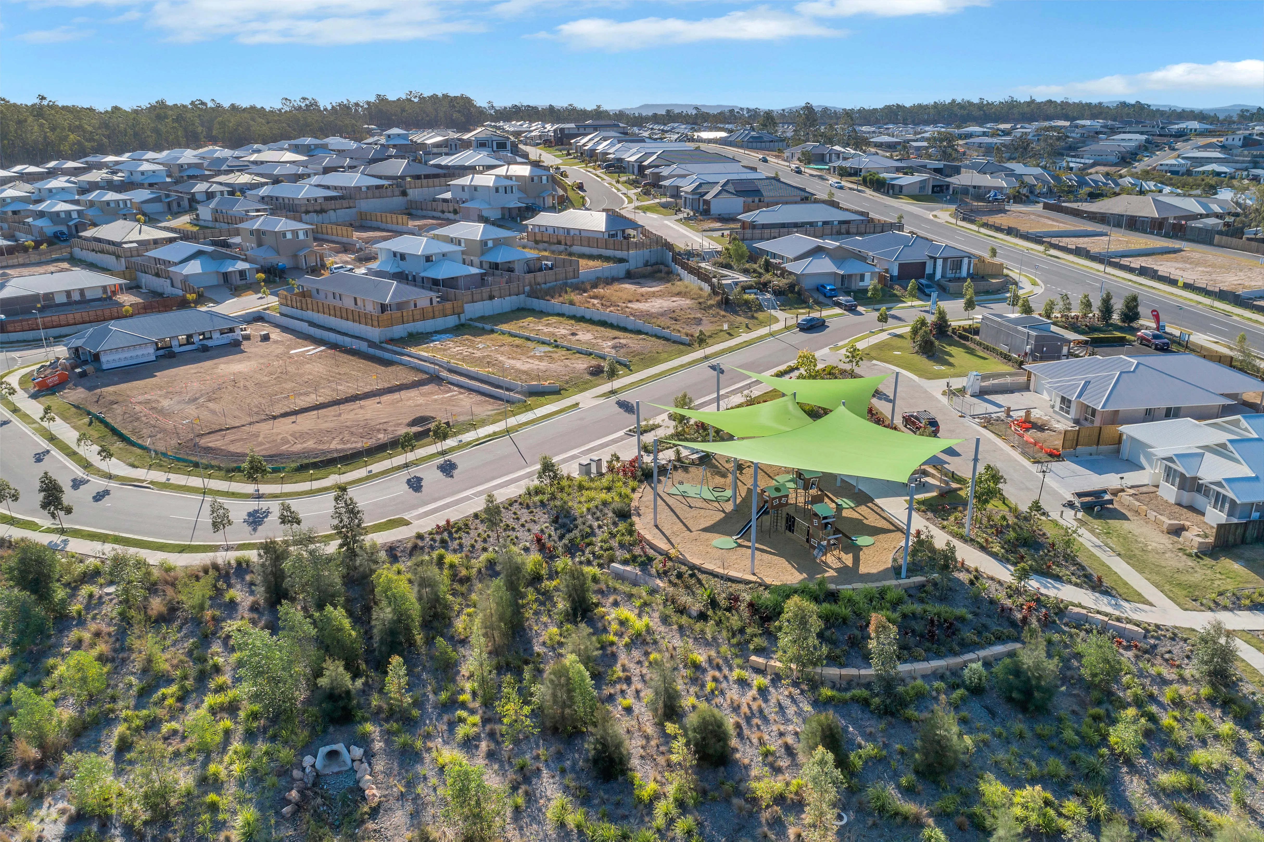 Aerial view of a new housing estate with a shaded playground and surrounding streets.