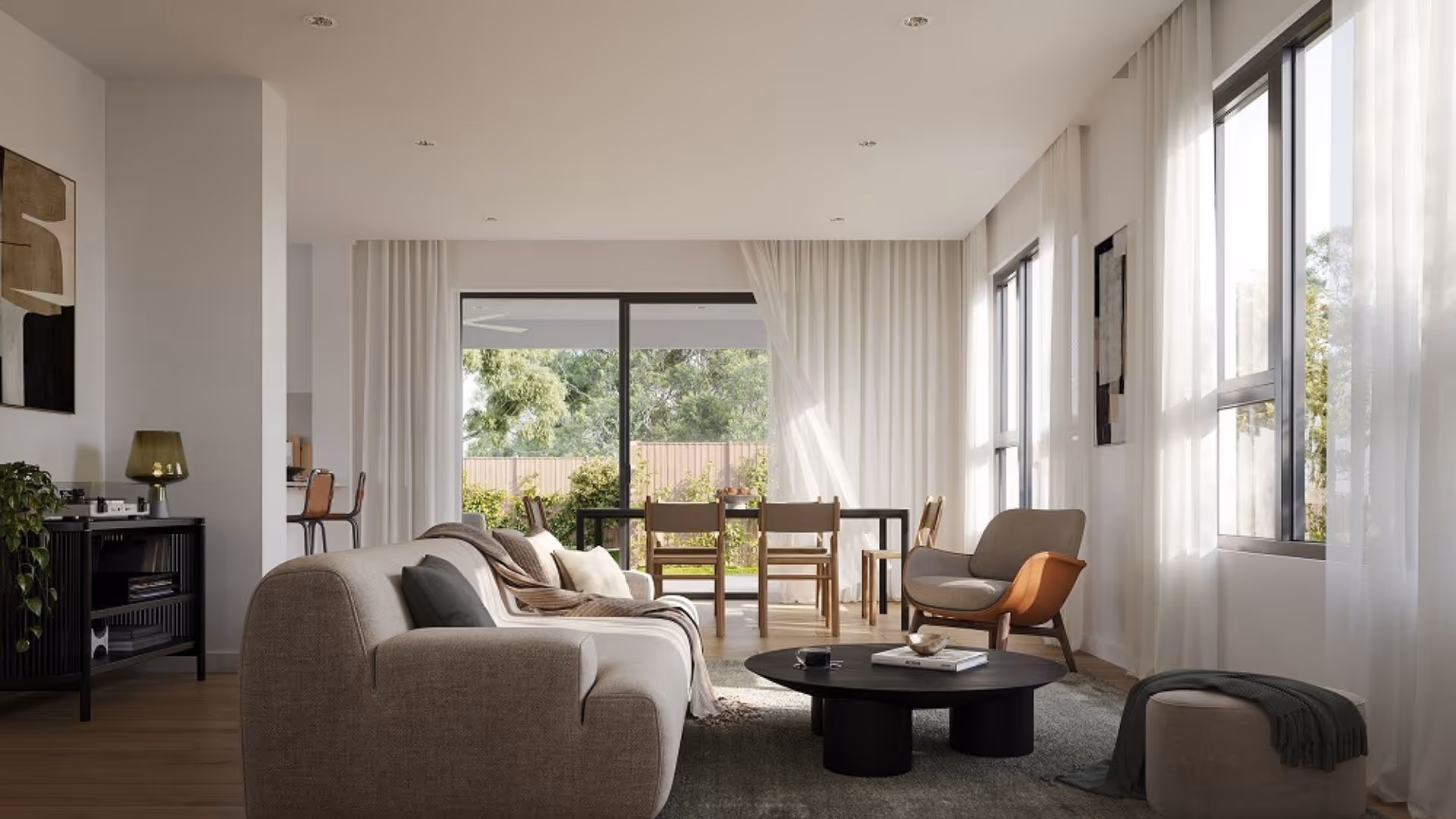Modern living and dining room with neutral furniture, large windows with sheer curtains, and sliding doors opening to a green backyard.