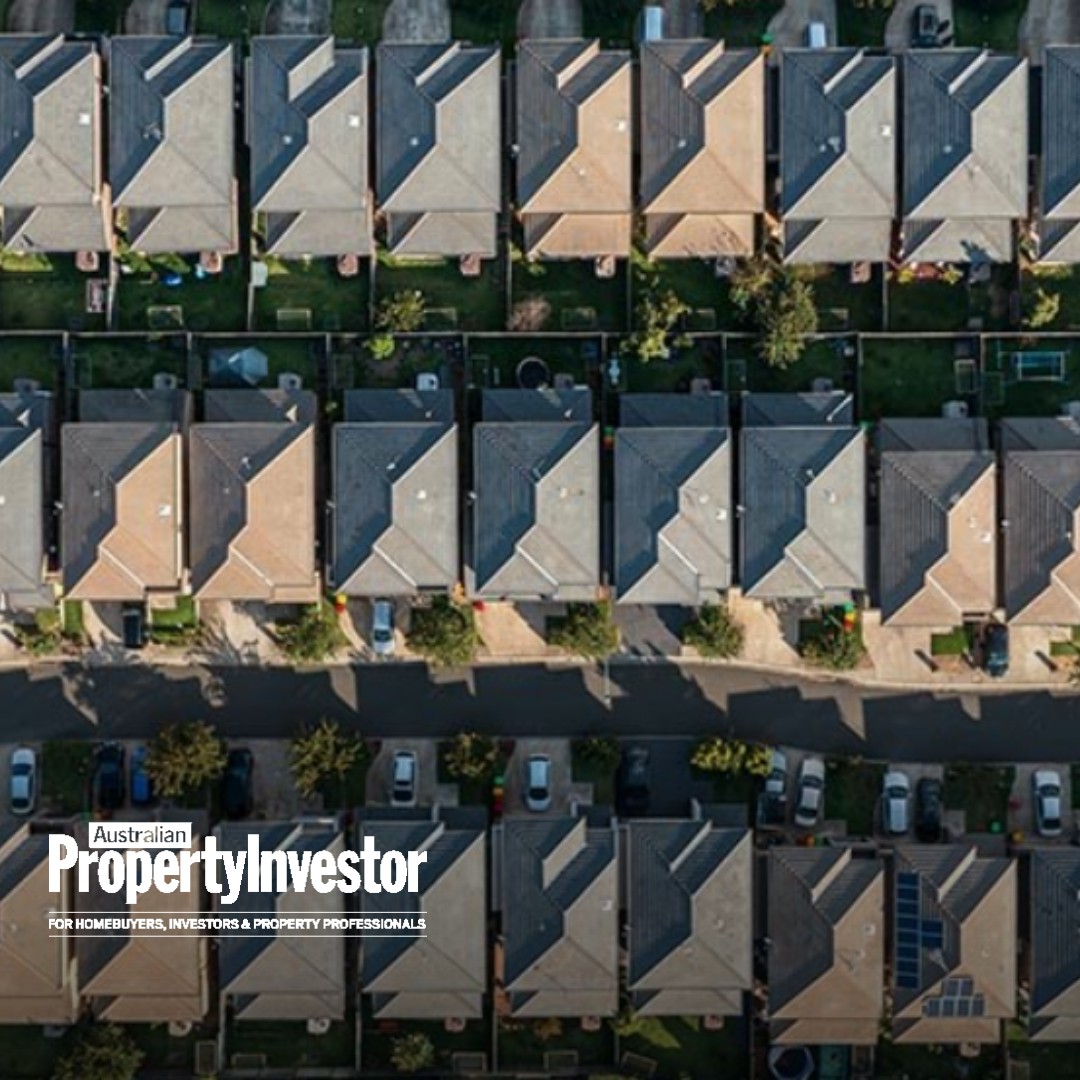 Aerial view of rows of suburban houses with hipped roofs, backyards and a street lined with parked cars, with the Australian Property Investor logo