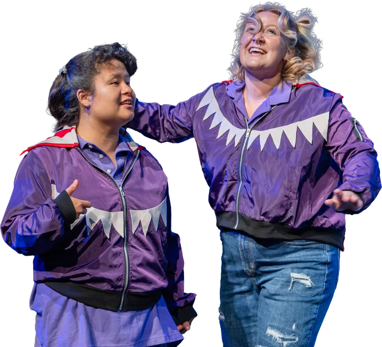 Two Tapestry actors in purple shark jackets laugh together on stage in Finding Nemo Jr.