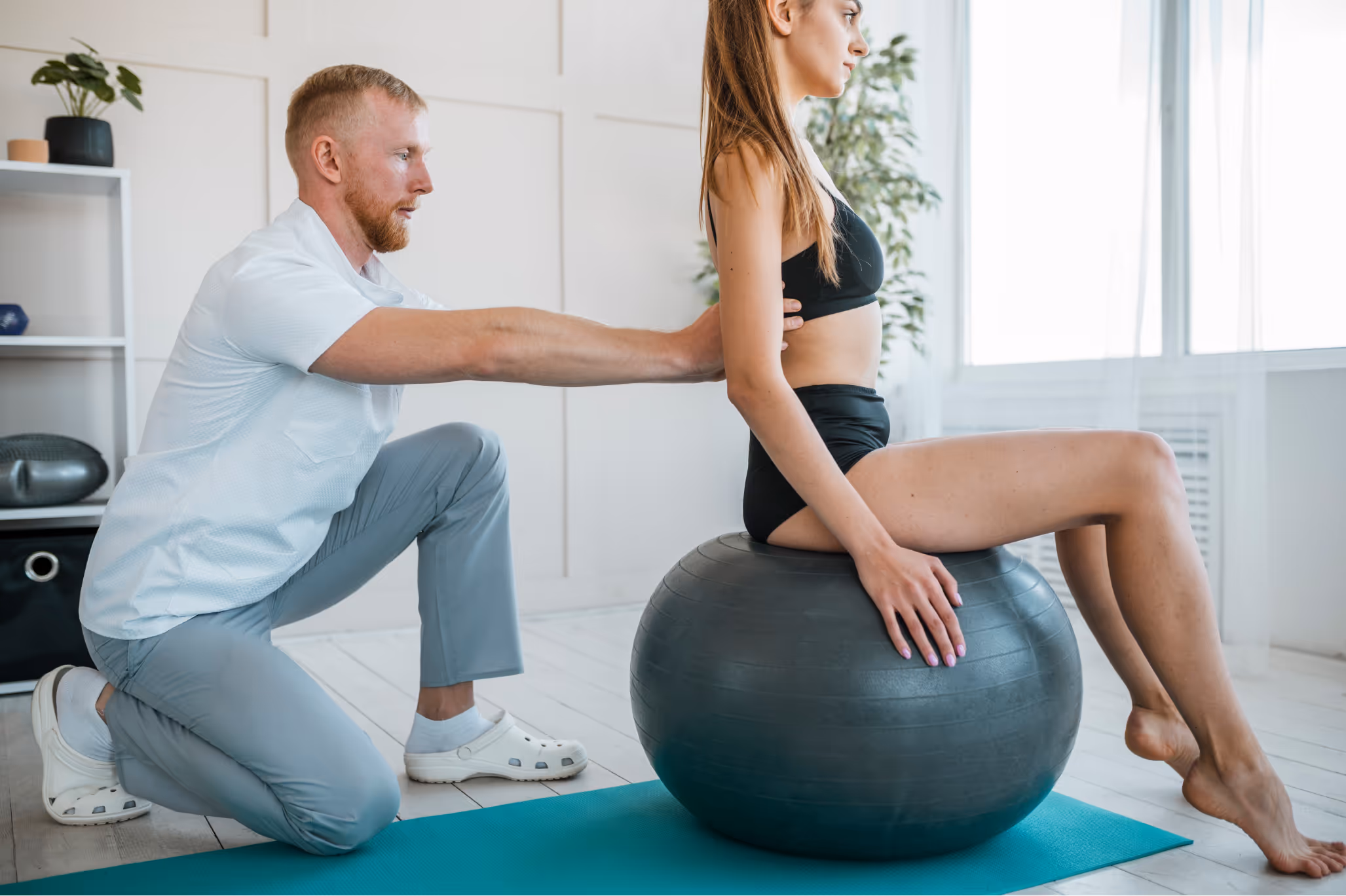 Trainer with client sitting on the fitball