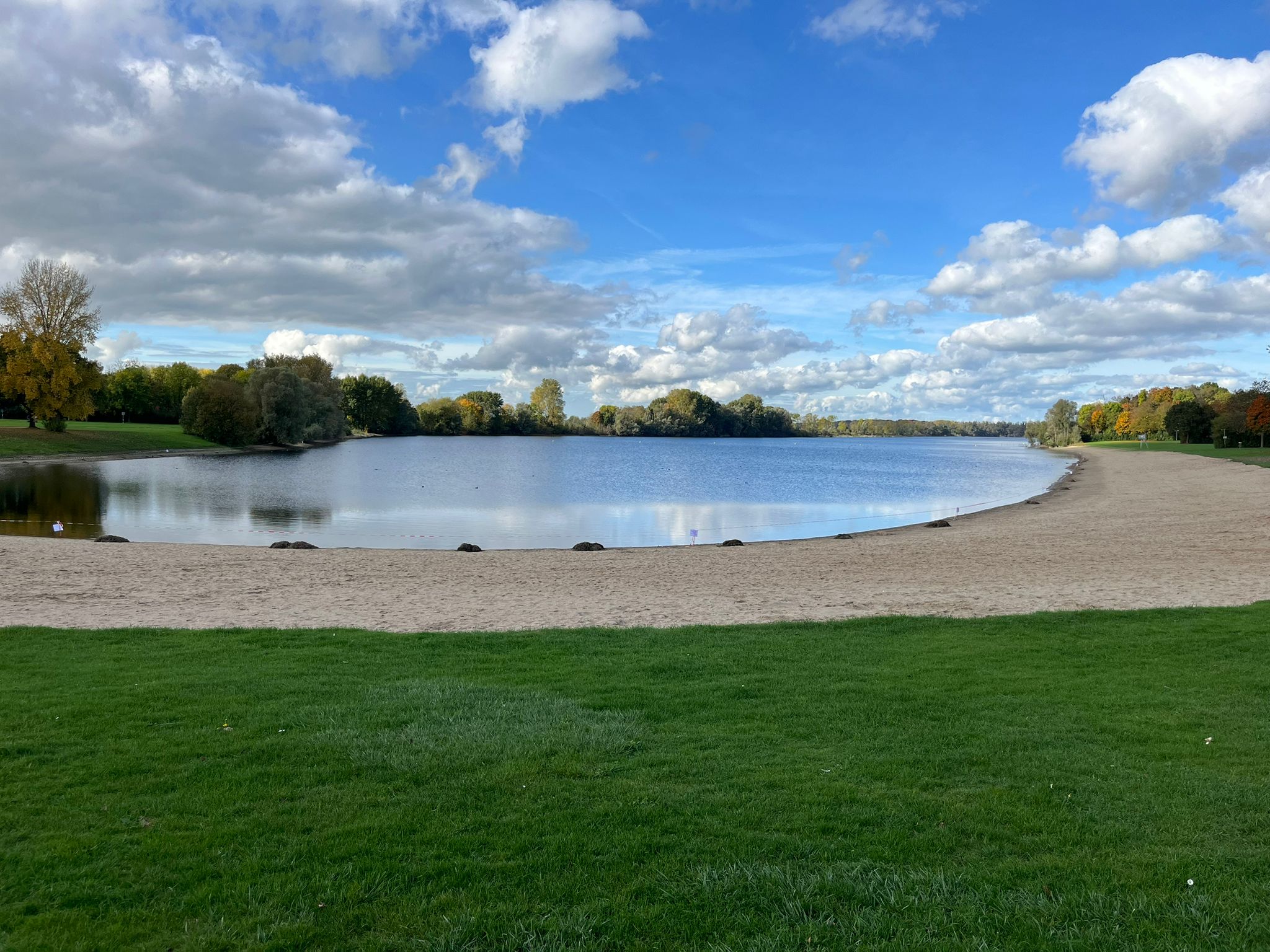 Blick über den Auesee in Wesel mit Sandstrand und grüner Wiese bei sonnigem Wetter
