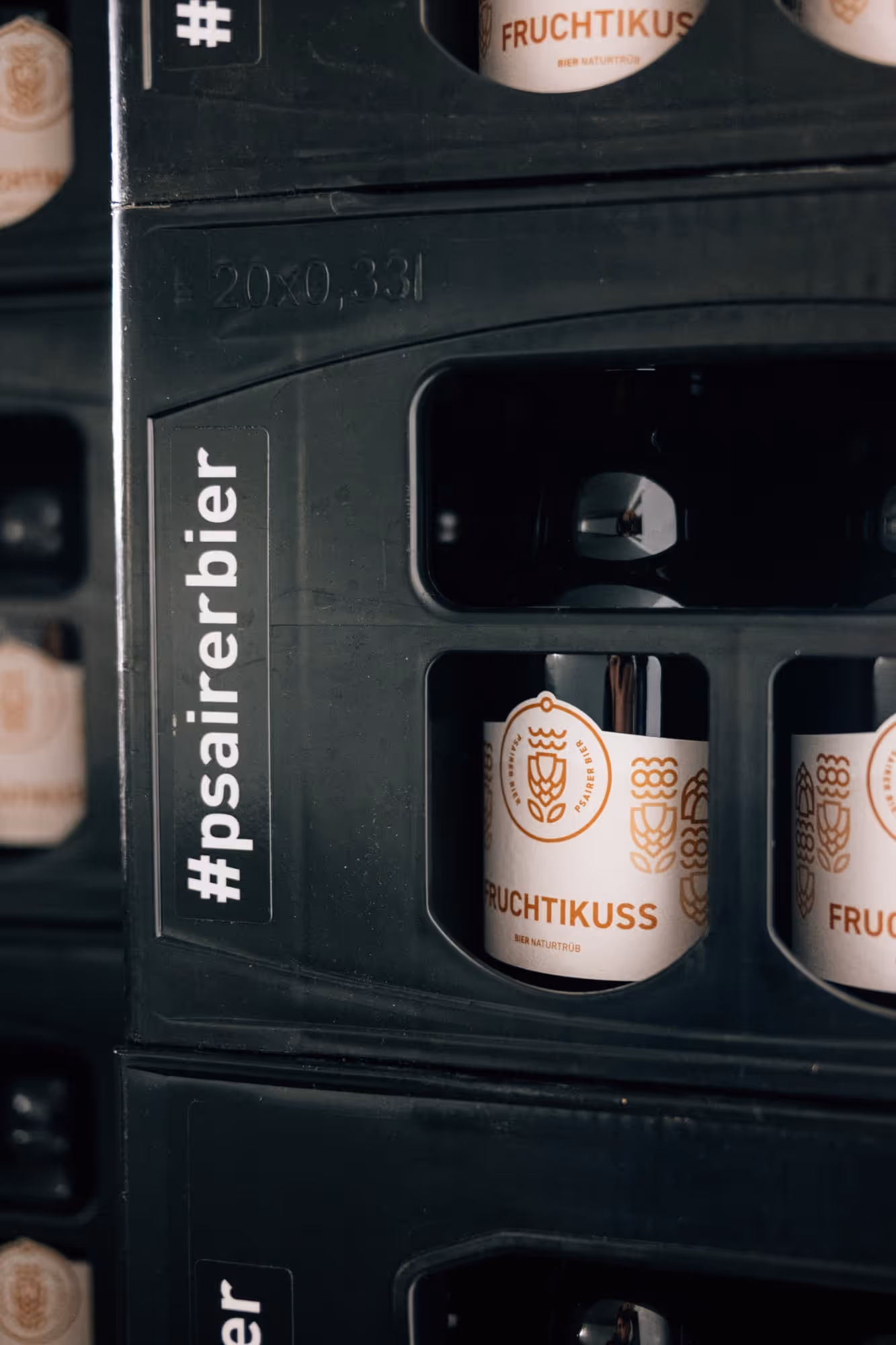 Mehrere Bierflaschen mit dem Etikett 'Fruchtikus' in einem schwarzen Kasten mit dem Aufkleber #psairerbier.
