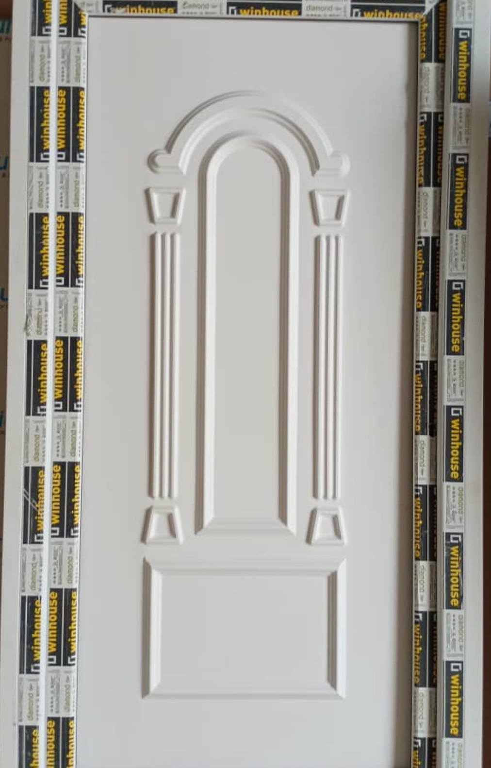 لوحة باب بيضاء wpc تتميز بتصميم مستطيل مقوس مرتفع مع قوالب زخرفية.