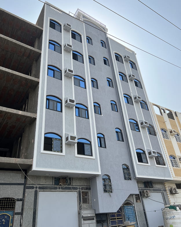 مبنى شاهق به صفوف متعددة من النوافذ المقوسة upvc والعديد من وحدات تكييف الهواء الخارجية في يوم صافٍ.