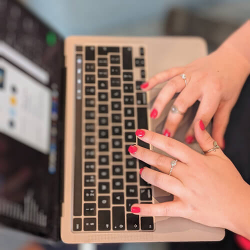 Close-up of Rachels hands with pink nail polish typing on a laptop keyboard