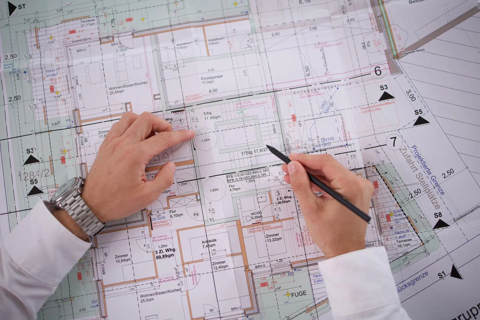 Grundriss-Plan eines Gebäudes mit Händen, die einen Stift halten.