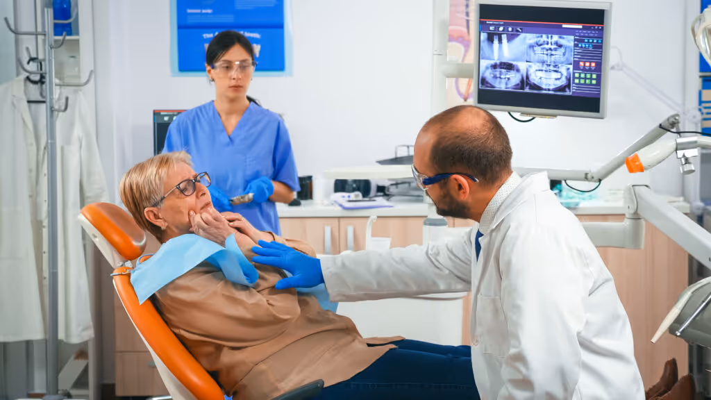 Ein Zahnarzt und eine Assistentin behandeln einen Patienten auf einem Zahnarztstuhl.