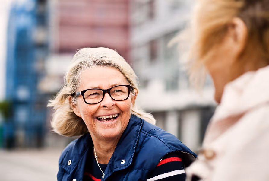 Eine ältere Frau mit Brille, die lacht.